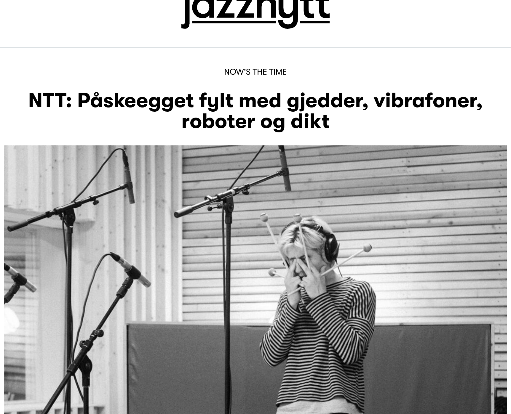 Black and white photo of blonde person in striped shirt covering face with hands in recording studio with microphones and equipment visible