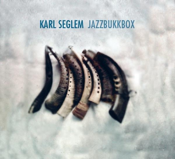 Album cover showing five curved horn instruments arranged in a fan pattern against a soft gray-white background with dreamy, ethereal lighting and texture.