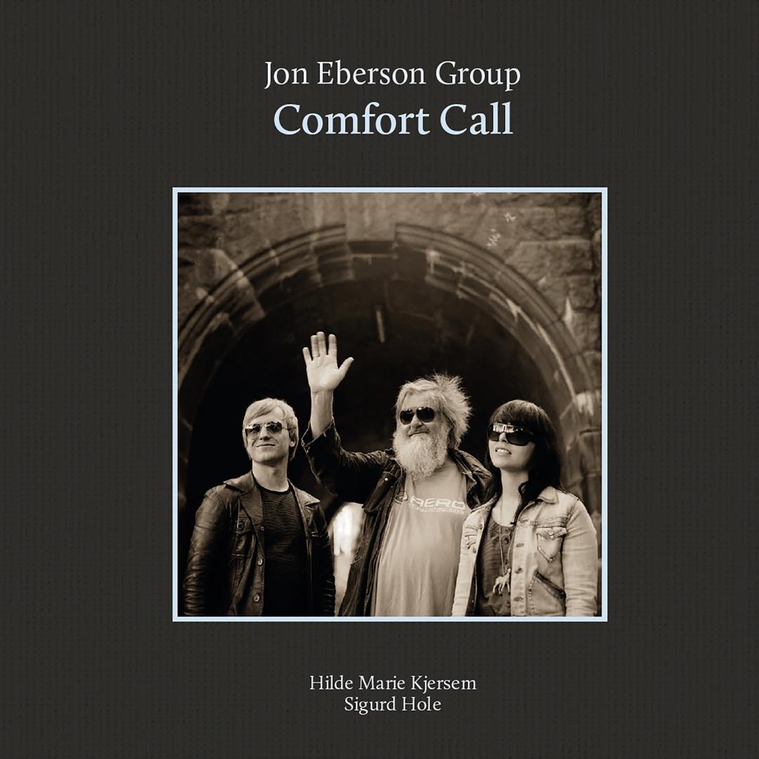 Three musicians in sunglasses pose in stone tunnel archway, sepia-toned album cover for Jon Eberson Group's "Comfort Call" with dark atmospheric mood
