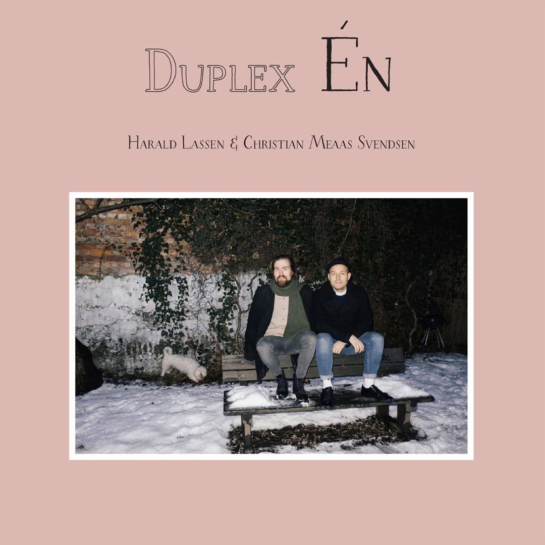 Pink album cover featuring two men sitting on a wooden bench in snow with ivy-covered brick wall behind them, titled "Duplex Én" by Harald Lassen & Christian Meaas Svendsen