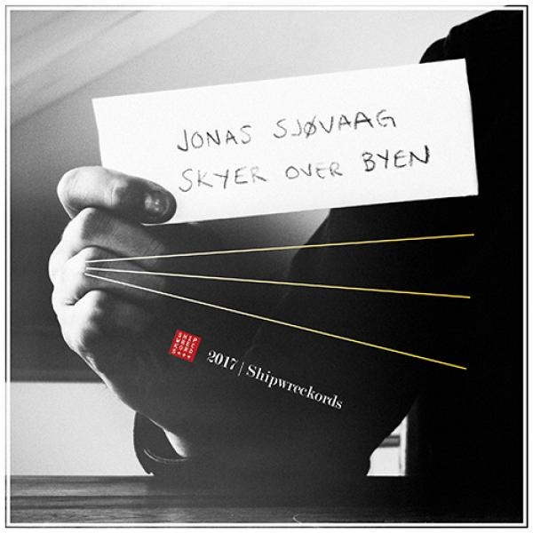 Black and white photo of hands holding vinyl record with handwritten note "JONAS SJØVAAG SKYER OVER BYEN" and red Shipwreckords label visible