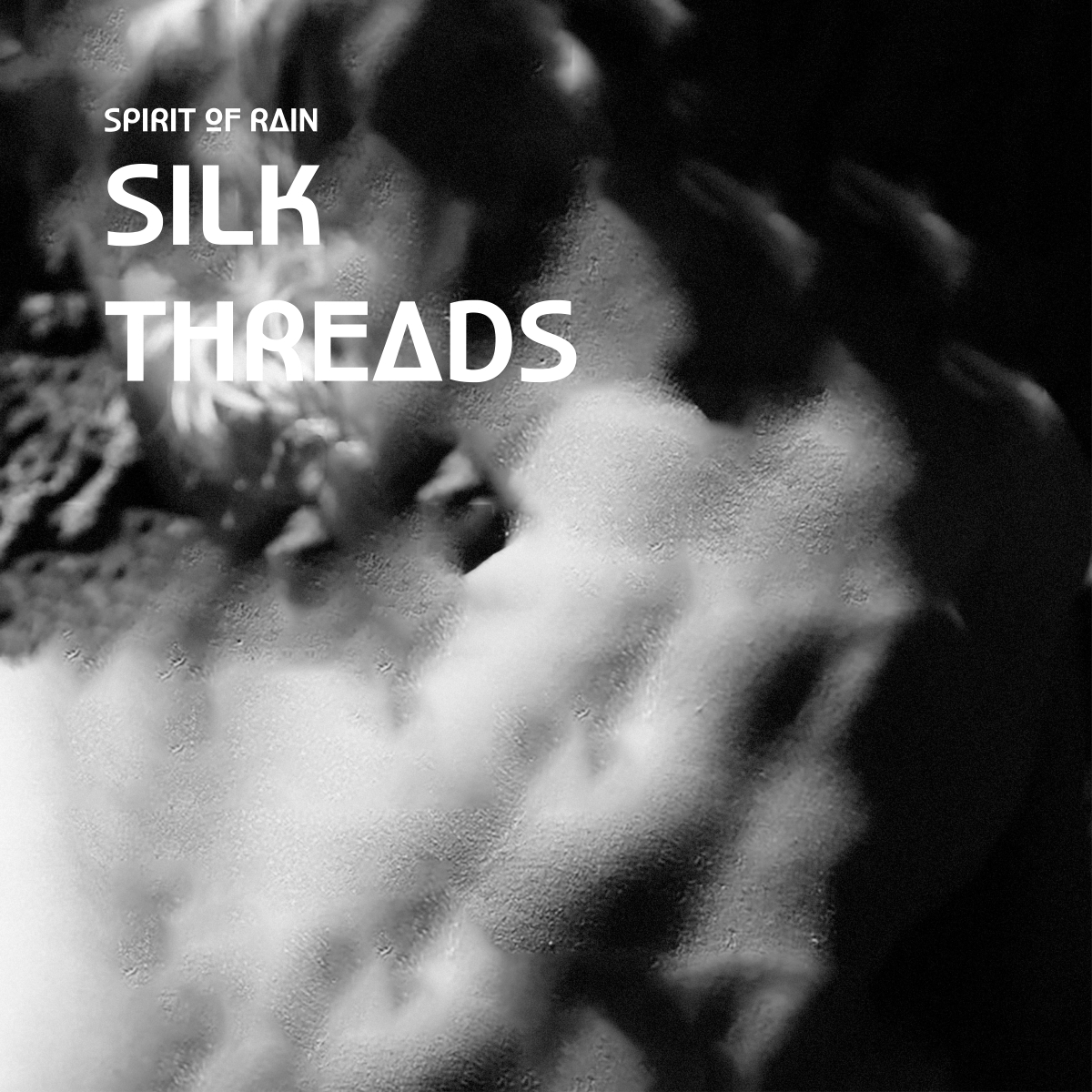 Black and white close-up of hands with water droplets, creating an intimate, moody atmosphere with "SPIRIT OF RAIN SILK THREADS" text overlay