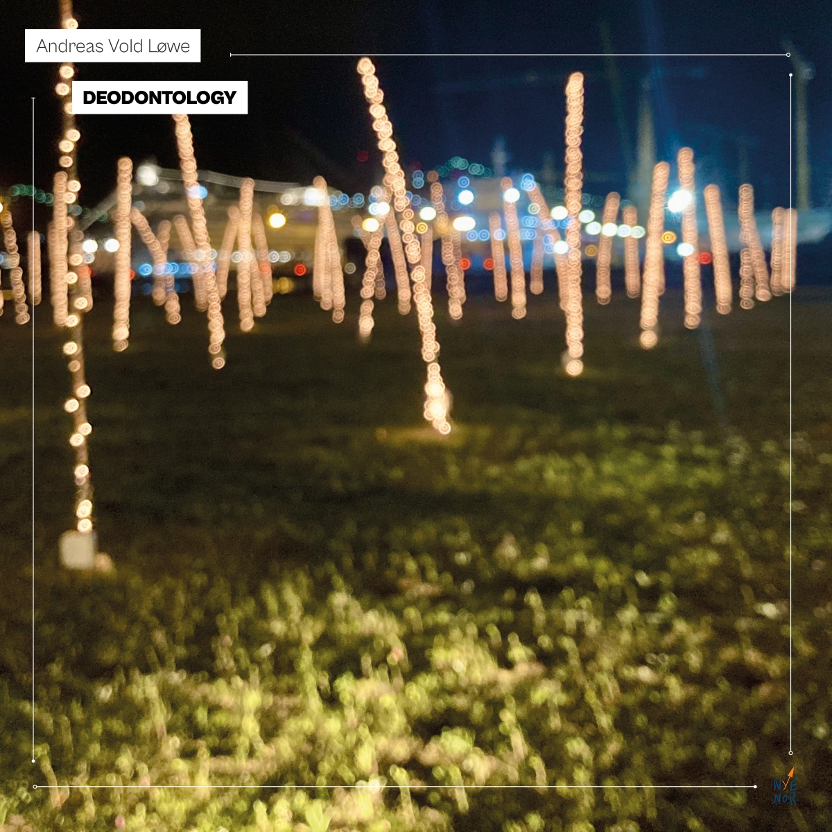 Blurred nighttime scene with warm bokeh lights creating vertical streaks against dark blue sky, yellow-green grass below, dreamy atmospheric mood