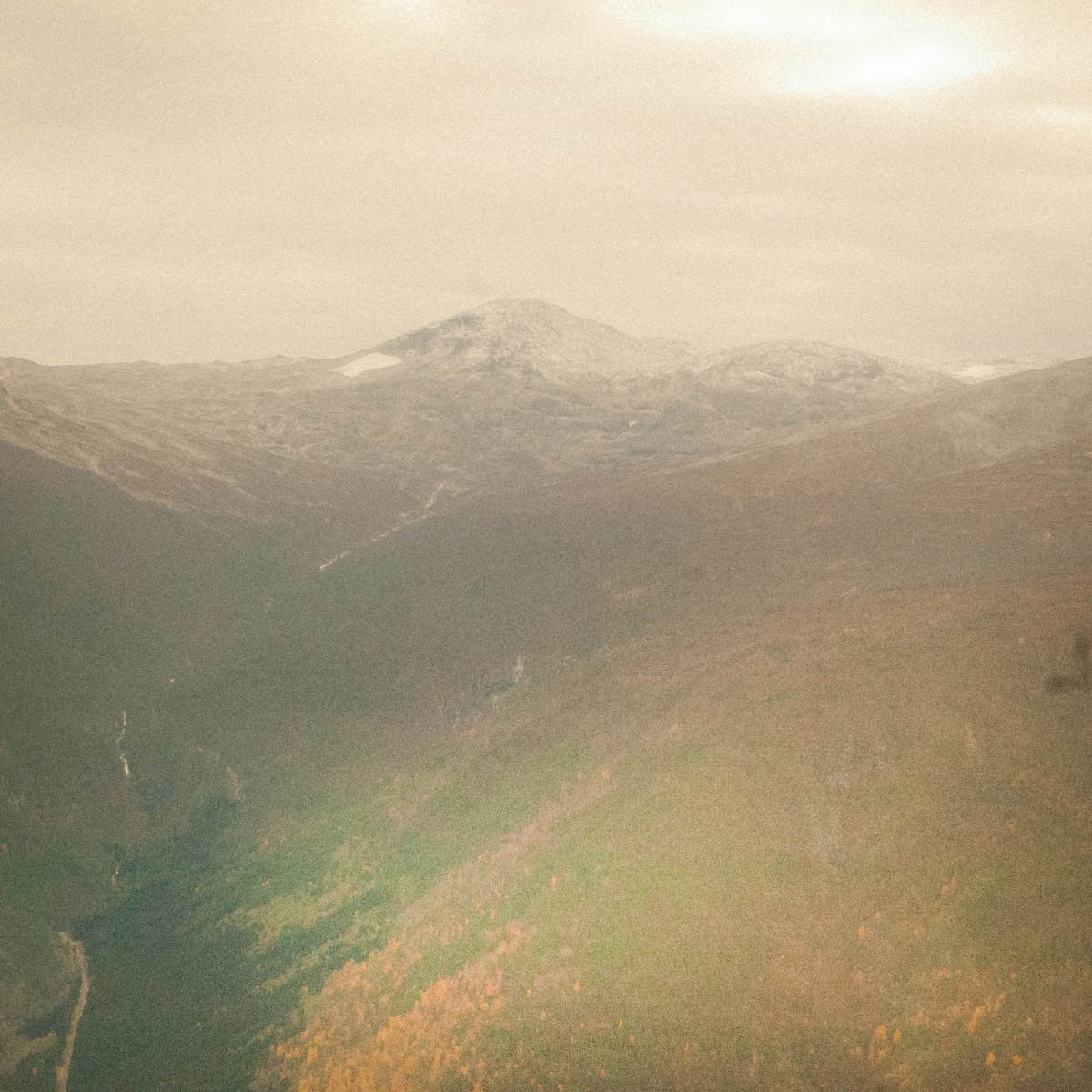 Misty mountain landscape in Sogn, Norway with rolling hills in muted earth tones and soft atmospheric haze creating a dreamy, ethereal mood.