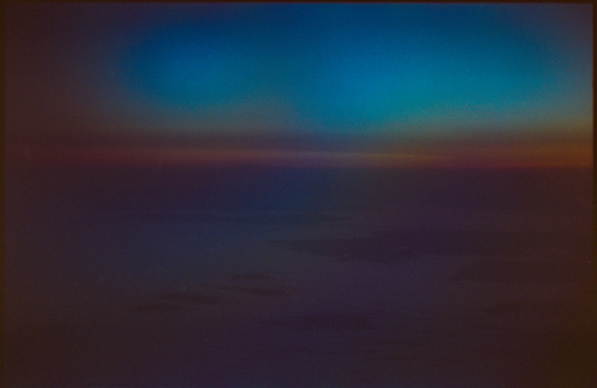 Blurred twilight horizon with deep blue sky transitioning to purple and orange hues, creating an abstract atmospheric mood
