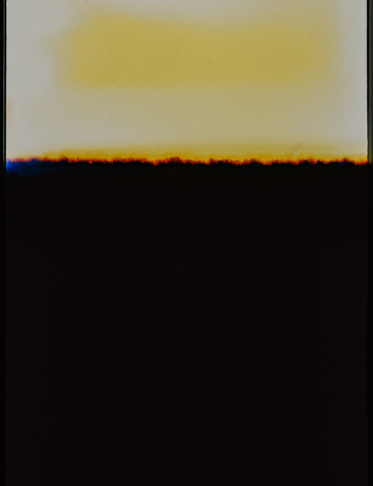 Abstract landscape with golden yellow sky above dark silhouetted horizon line with orange-red glow, creating moody atmospheric composition