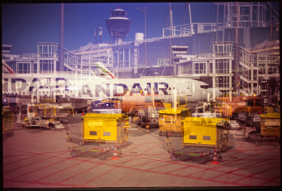 Purple-tinted airport tarmac scene with Armandair aircraft, yellow ground equipment, control tower, and industrial infrastructure creating vintage film aesthetic