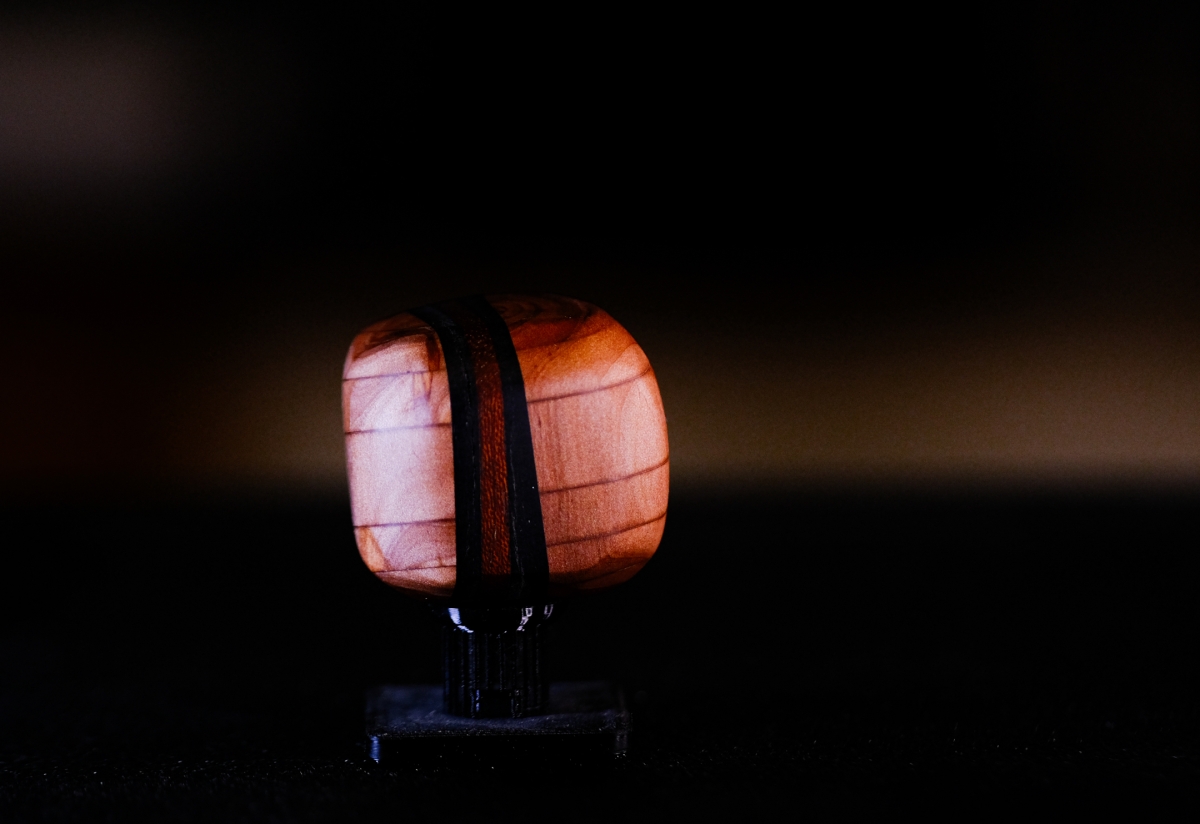 Illuminated sculptural lamp with twin orange-pink translucent panels on dark base, glowing warmly against black background in moody lighting