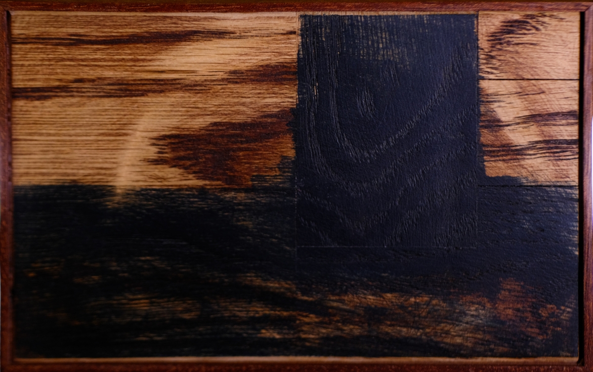 Wooden cutting board with natural grain and dark ebony inlay creating geometric pattern against black leather surface
