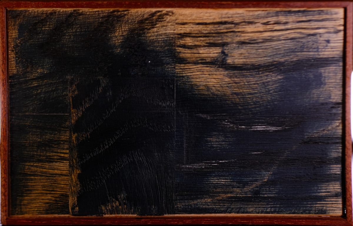 Dark wooden sculpture with carved tree silhouette in rectangular frame, showing contrasting wood grain textures and warm amber tones