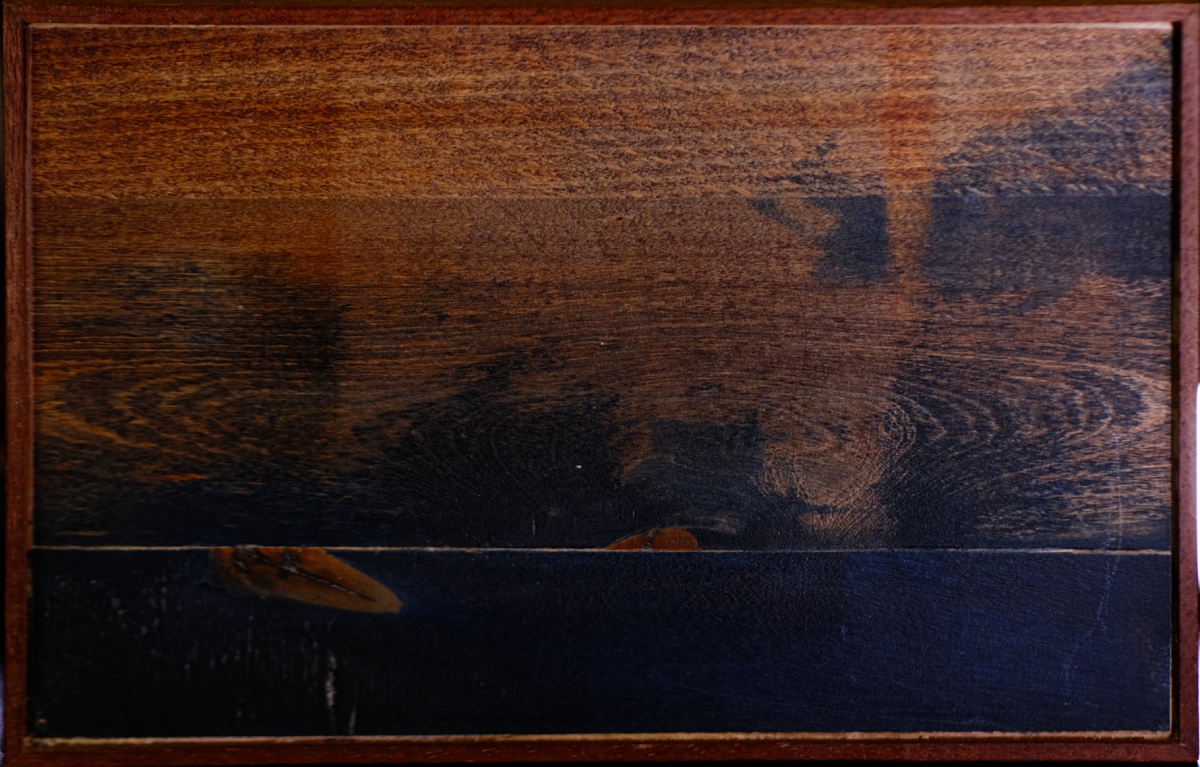 Dark wooden box with rich brown grain patterns and black lower section, displaying natural wood textures in warm lighting against dark background.