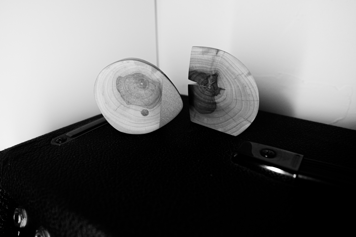 Two curved wood cross-sections with visible growth rings positioned in corner against white walls on dark wooden surface, black and white photograph