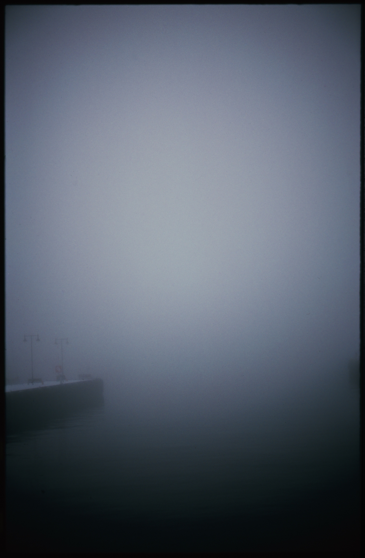 Moody atmospheric landscape with rolling hills silhouetted against overcast gray sky, creating misty ethereal mood with muted blue-gray tones