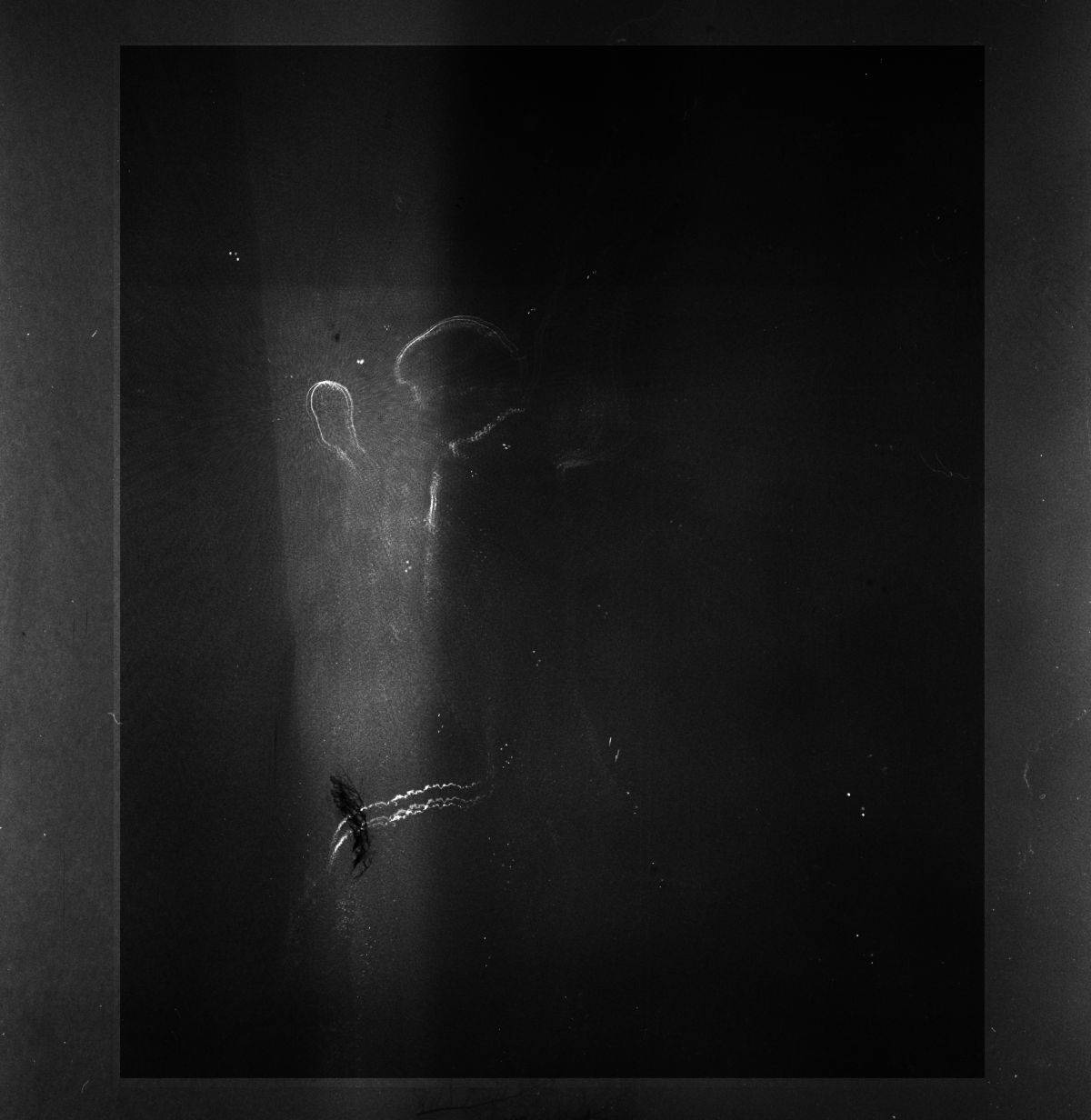 Dark, grainy black and white image showing silhouettes of two figures in atmospheric lighting with smoky or dusty effects