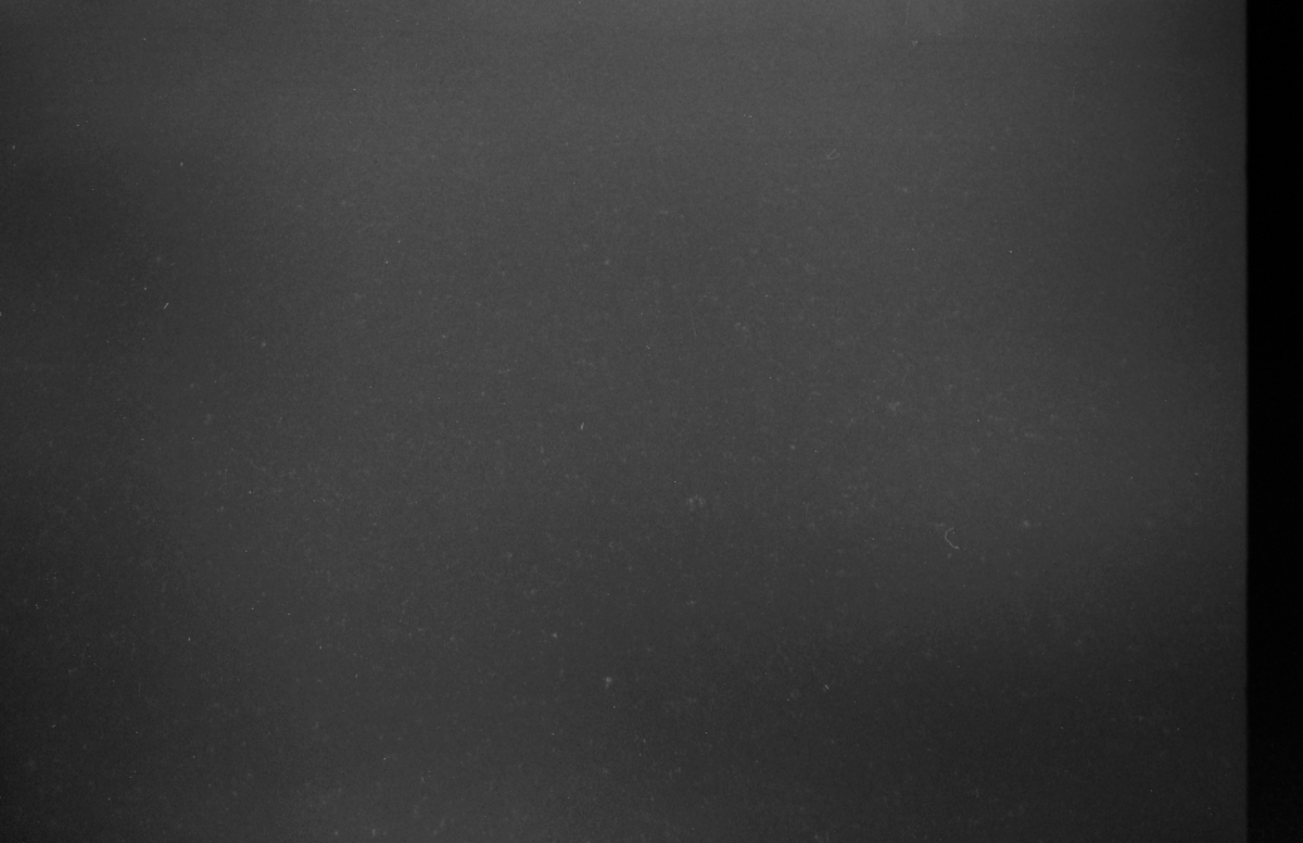 Dark gray textured surface with subtle grain and minor imperfections, creating a minimalist monochromatic composition with moody atmospheric lighting