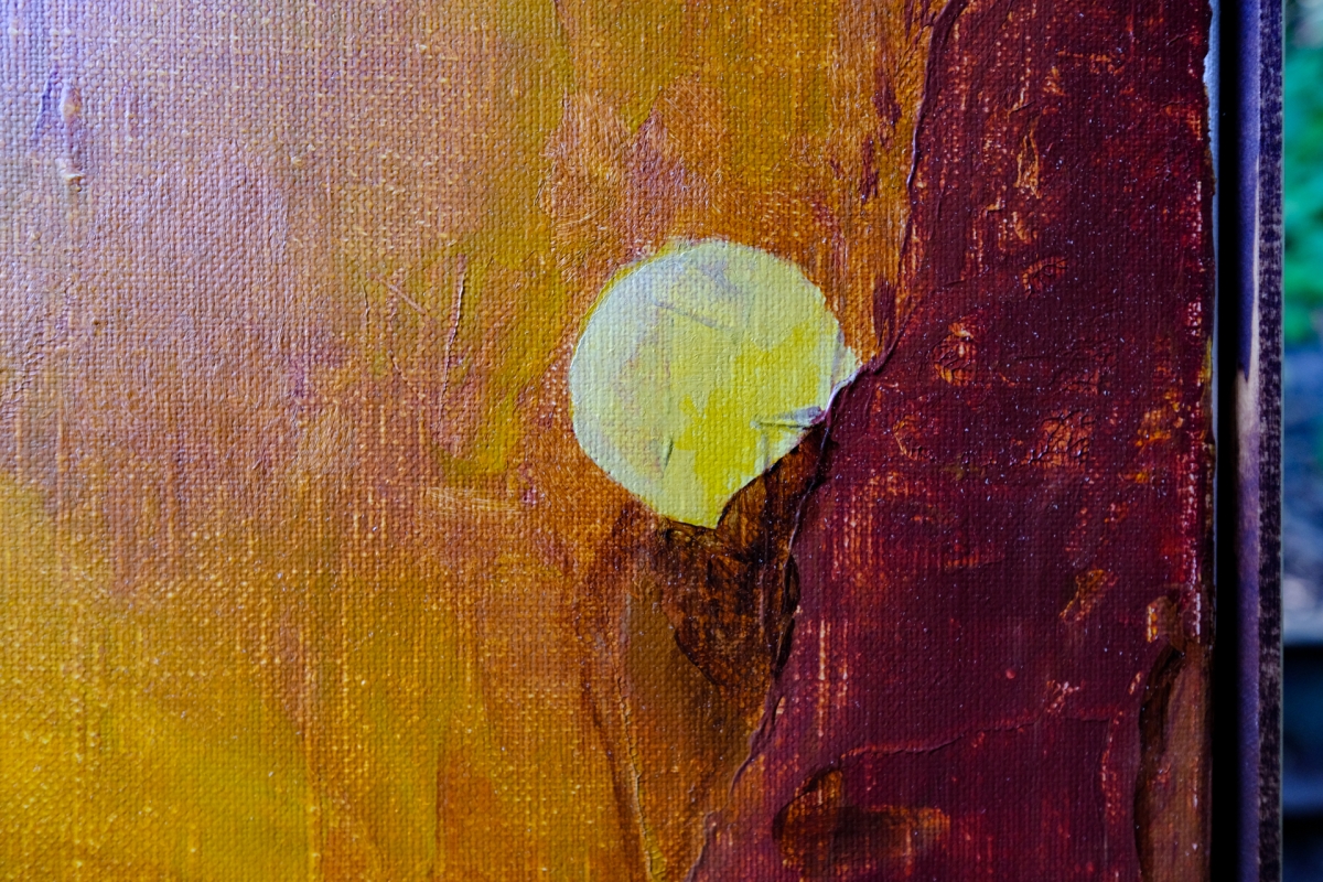 Close-up of textured canvas painting showing yellow-green circular form against warm orange and deep burgundy brushstrokes with visible paint layers