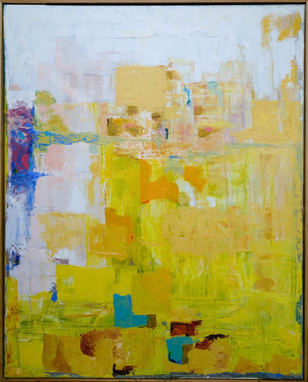 Abstract painting with vertical white-yellow beam and blue-green brushstrokes on gray background, framed in light wood, creating moody atmospheric composition.